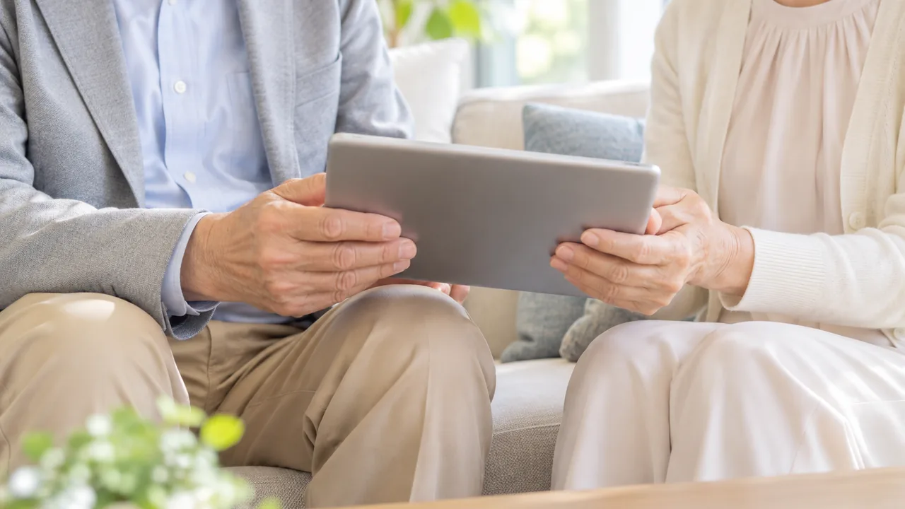 ソファで一緒にタブレットを持つシニアの夫婦の手元